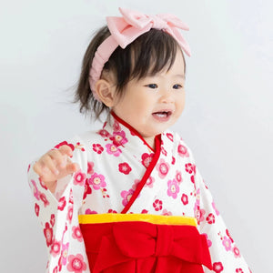 寶寶穿著紅色梅花和服連身衣進行新年或節慶拍照的可愛造型。